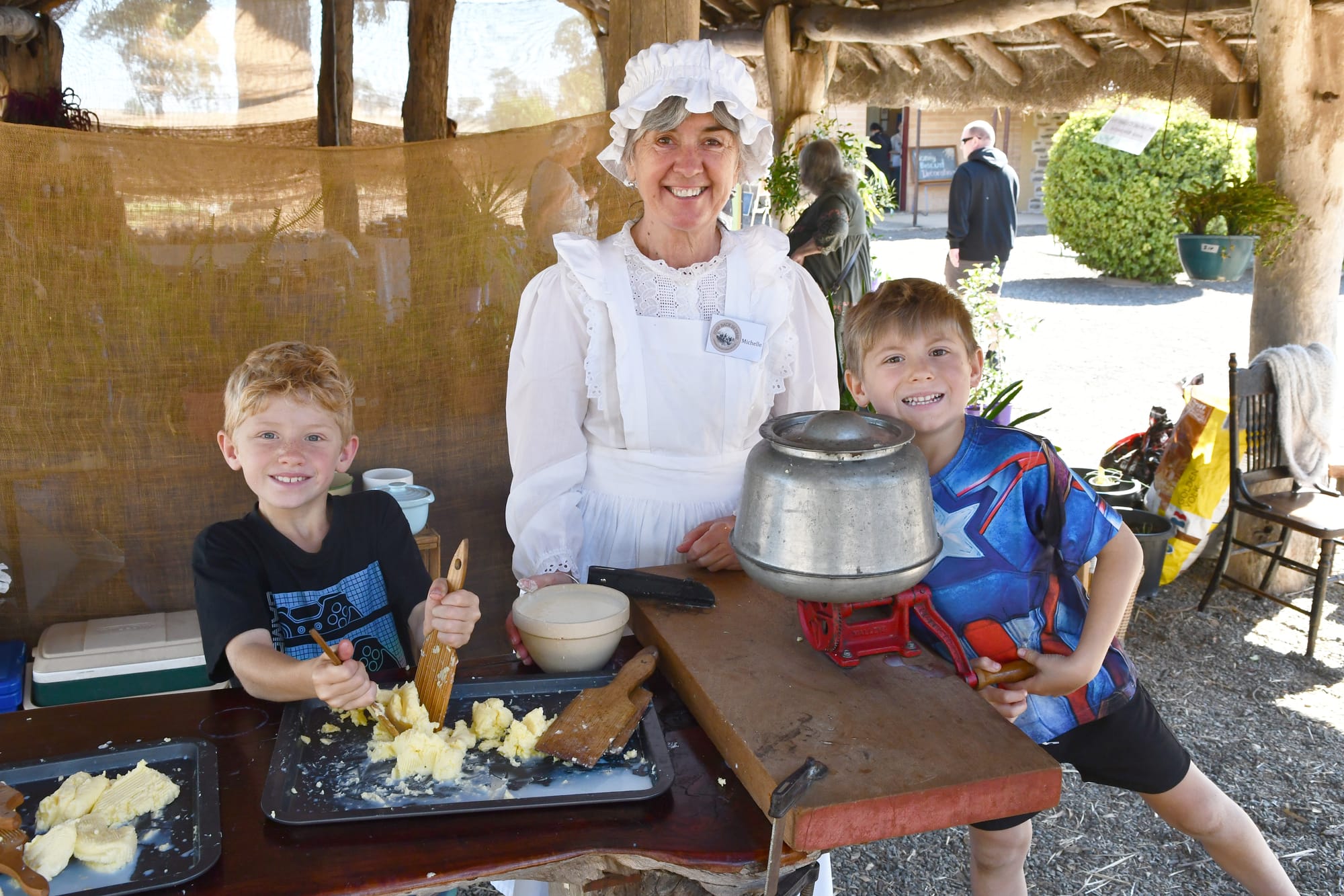Wednesday - Step Back in Time: Michelle Mylius (centre) shows Liam and Mason Lowke from Nuriootpa how to churn butter Photo. by Clem Stanley